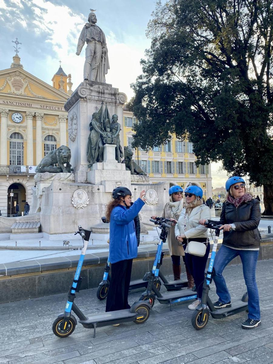 a group of people with scooters in front of a statue