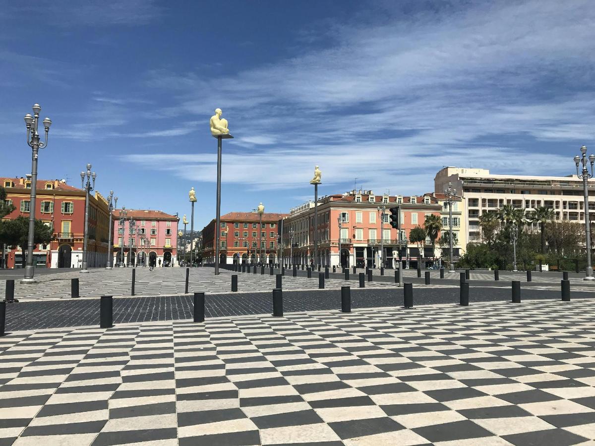 a statue on a pole in a square with buildings