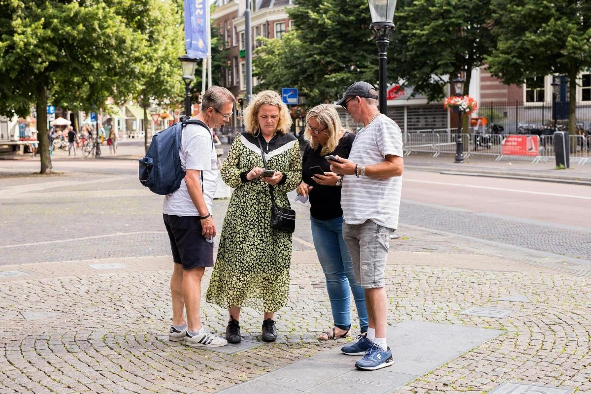 a group of people standing on a sidewalk looking at a cell phone