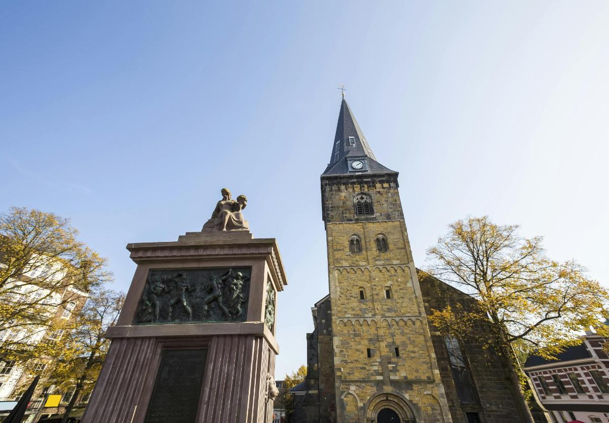 a tall clock tower with a statue in front of a building