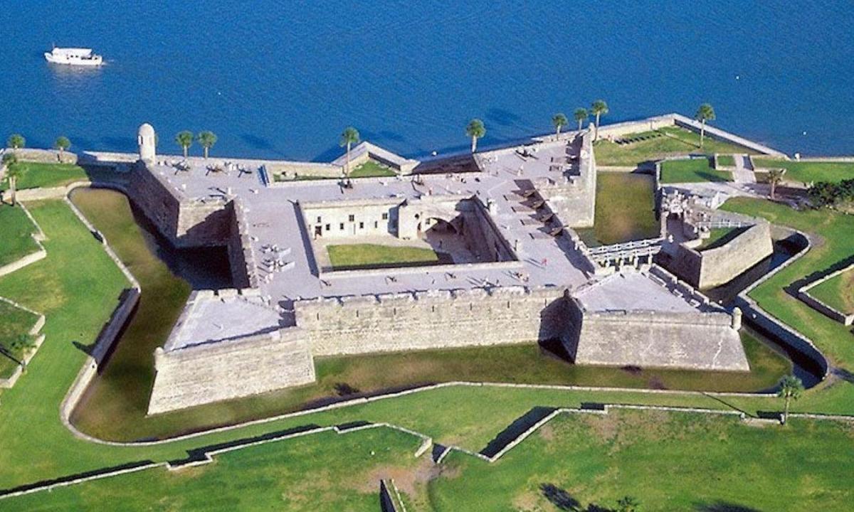 an aerial view of a building with the ocean in the background