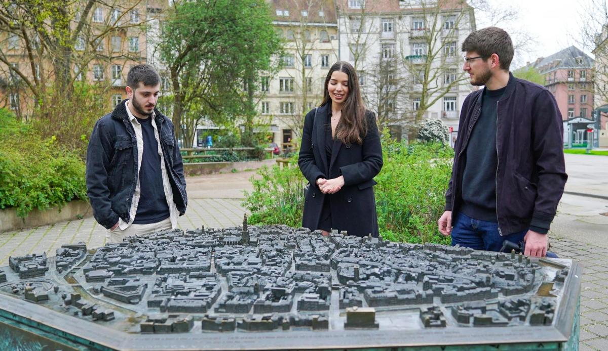 a group of three people standing next to a map