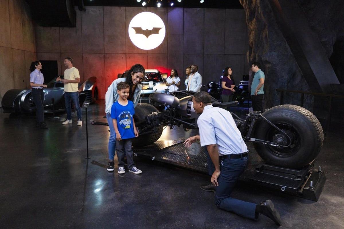 a group of people standing around a batman car