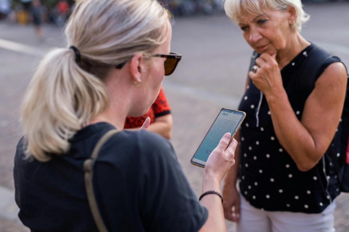 two women standing next to each other looking at a tablet