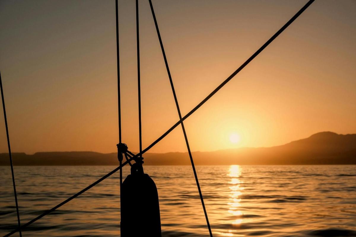 a boat in the ocean with the sunset in the background