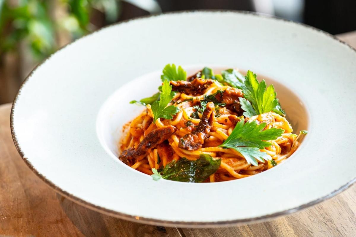 a white bowl of pasta with meat and herbs
