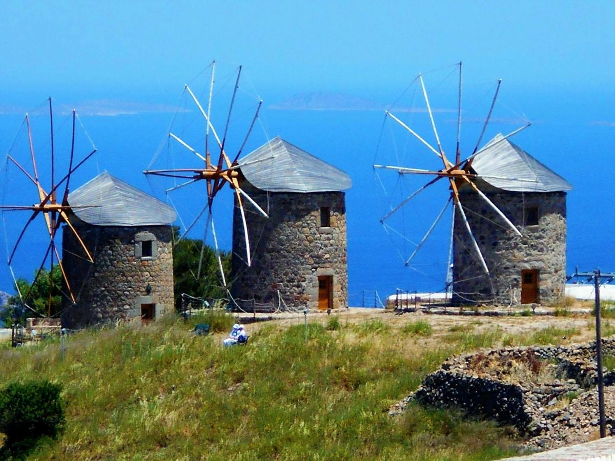 two windmills on a hill with the ocean in the background