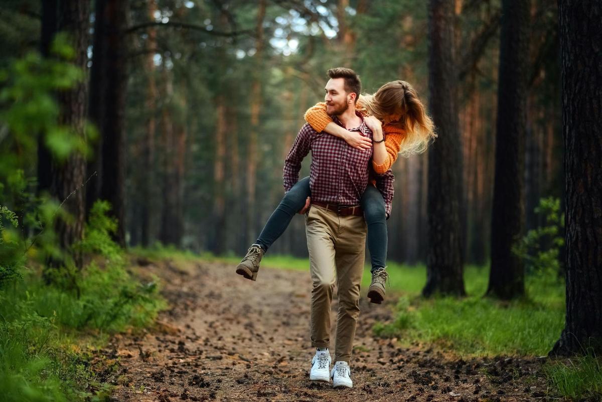a man carrying a woman in the woods