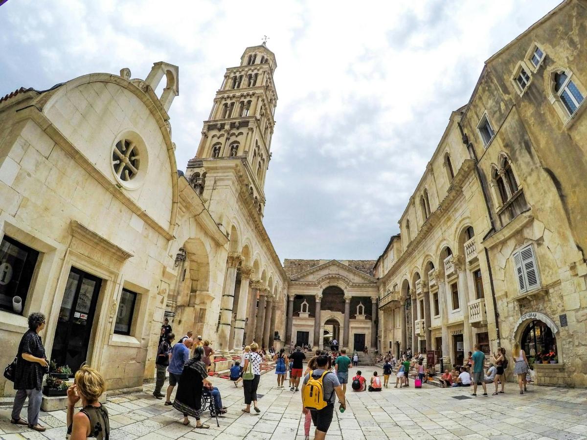 a group of people walking around a building with a clock tower