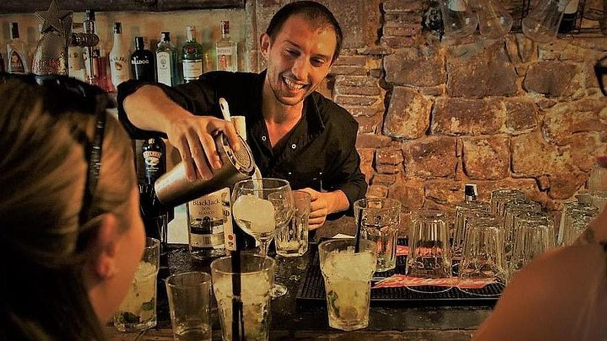a man pouring wine into a glass at a bar