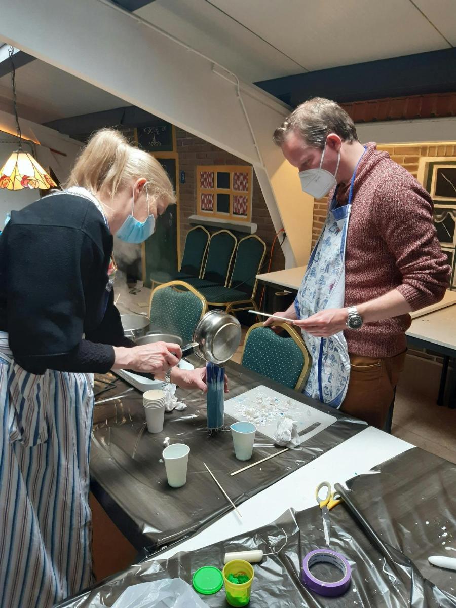 two people wearing face masks standing at a table with cups