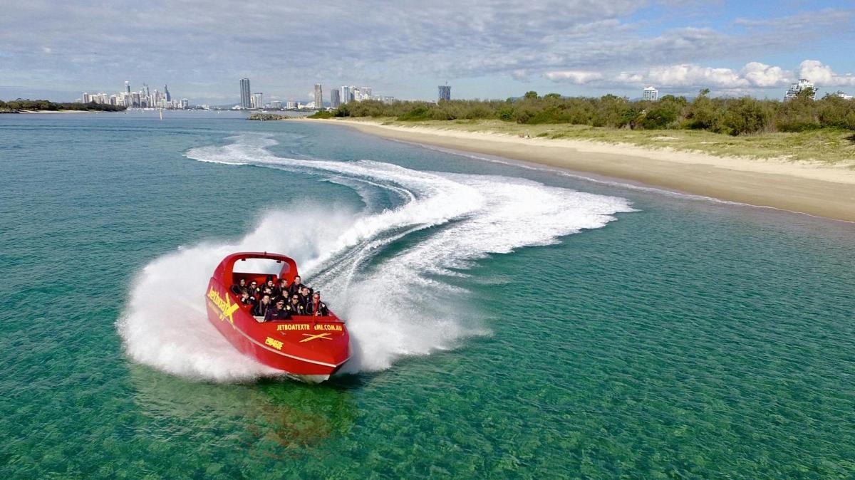 a red boat in the water next to a beach