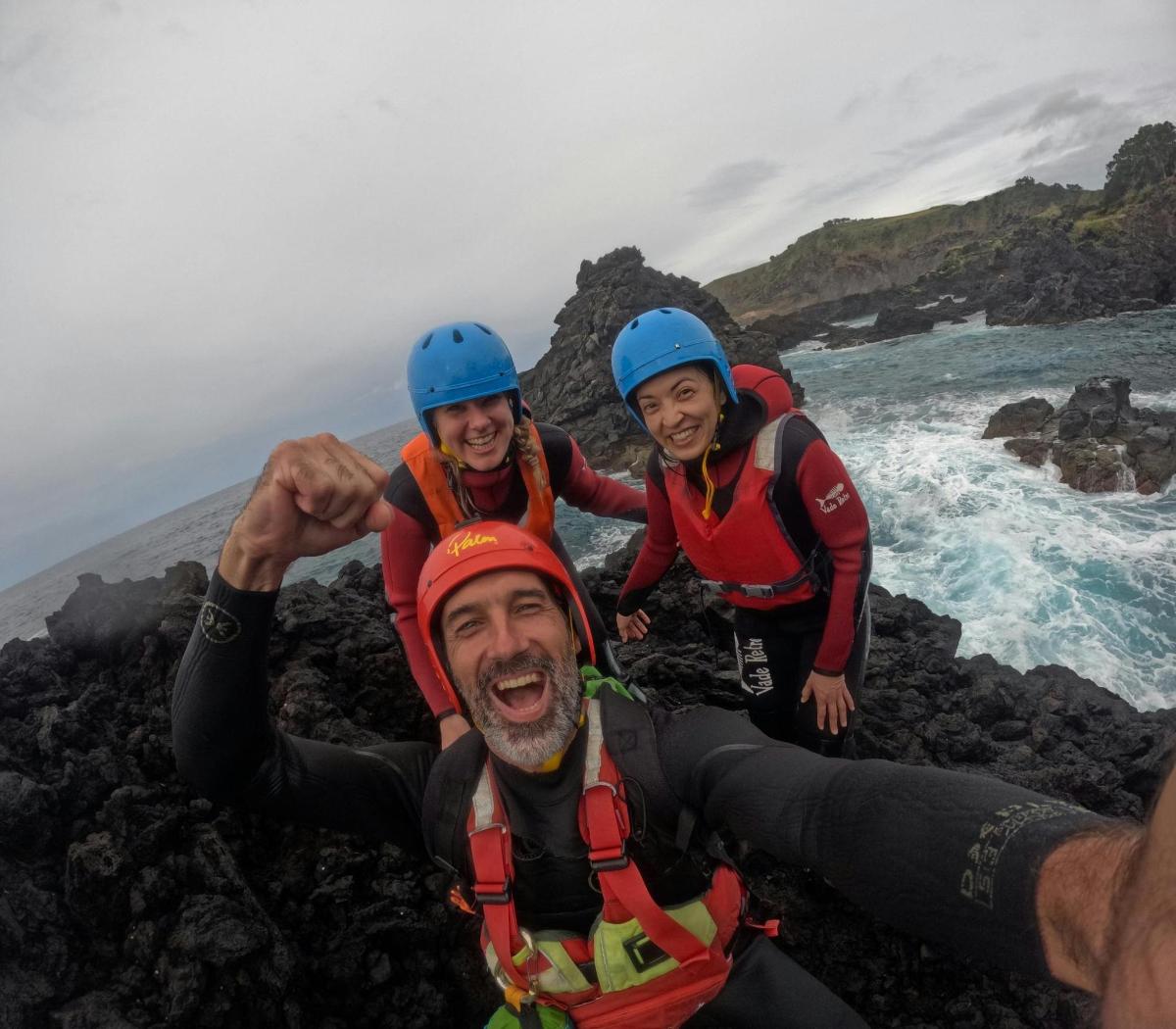a group of three people laying on rocks near the ocean
