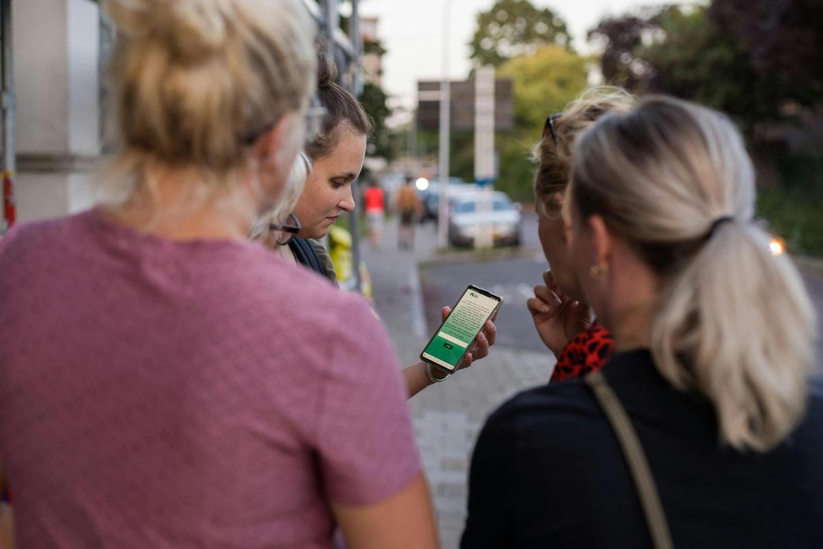 a group of women walking down a street looking at a cell phone