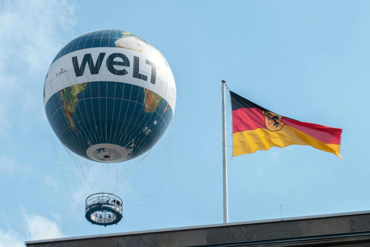 a hot air balloon flying next to a flag