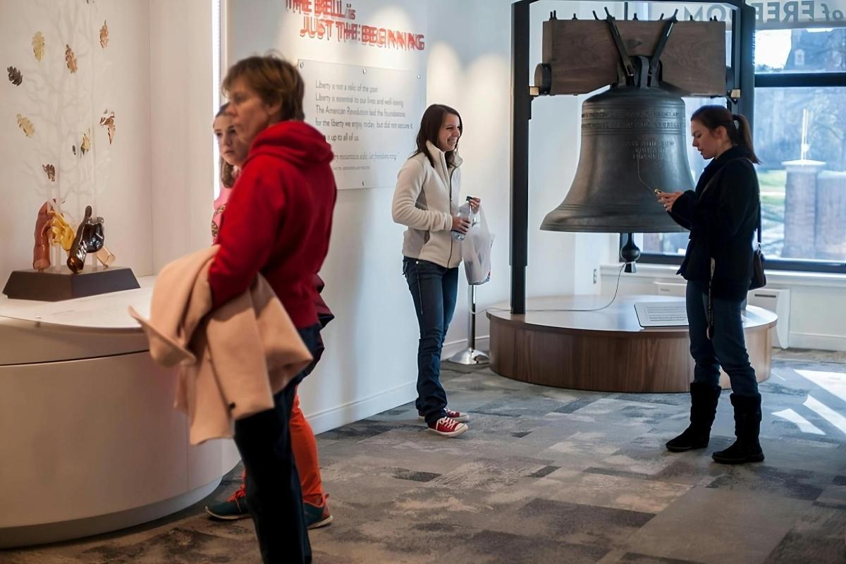 a group of people standing around a liberty bell