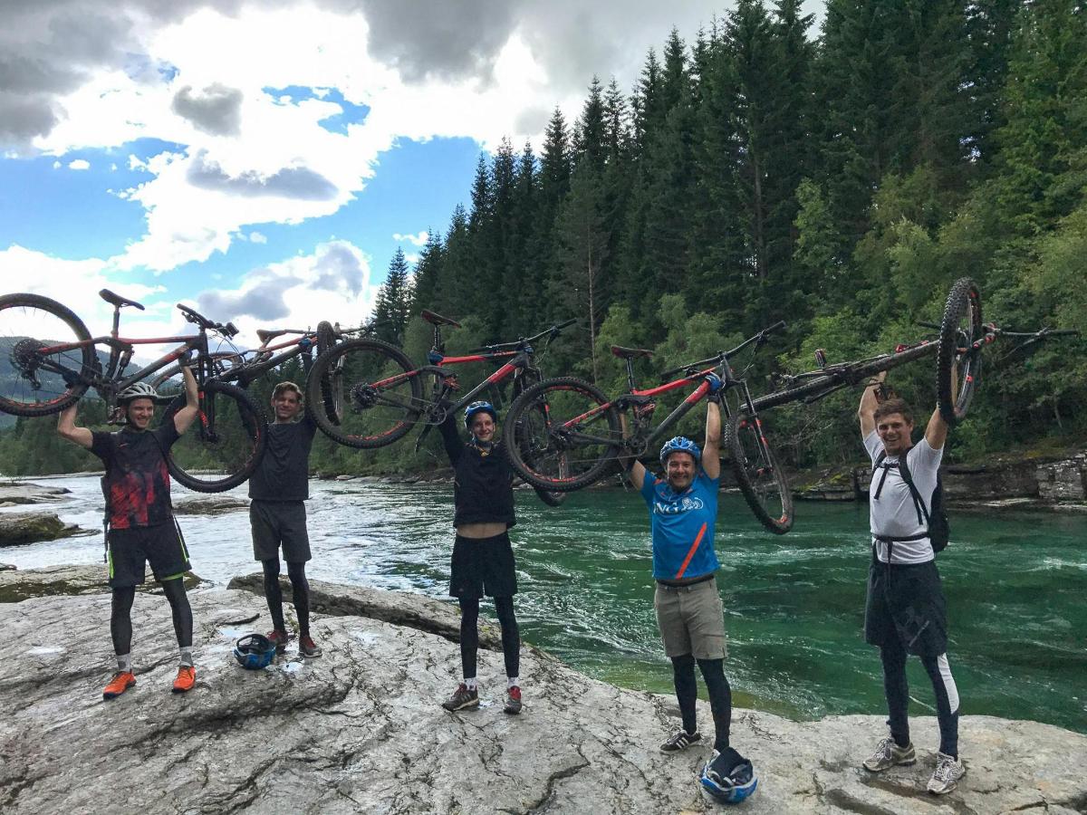 a group of men holding up their bikes on a river