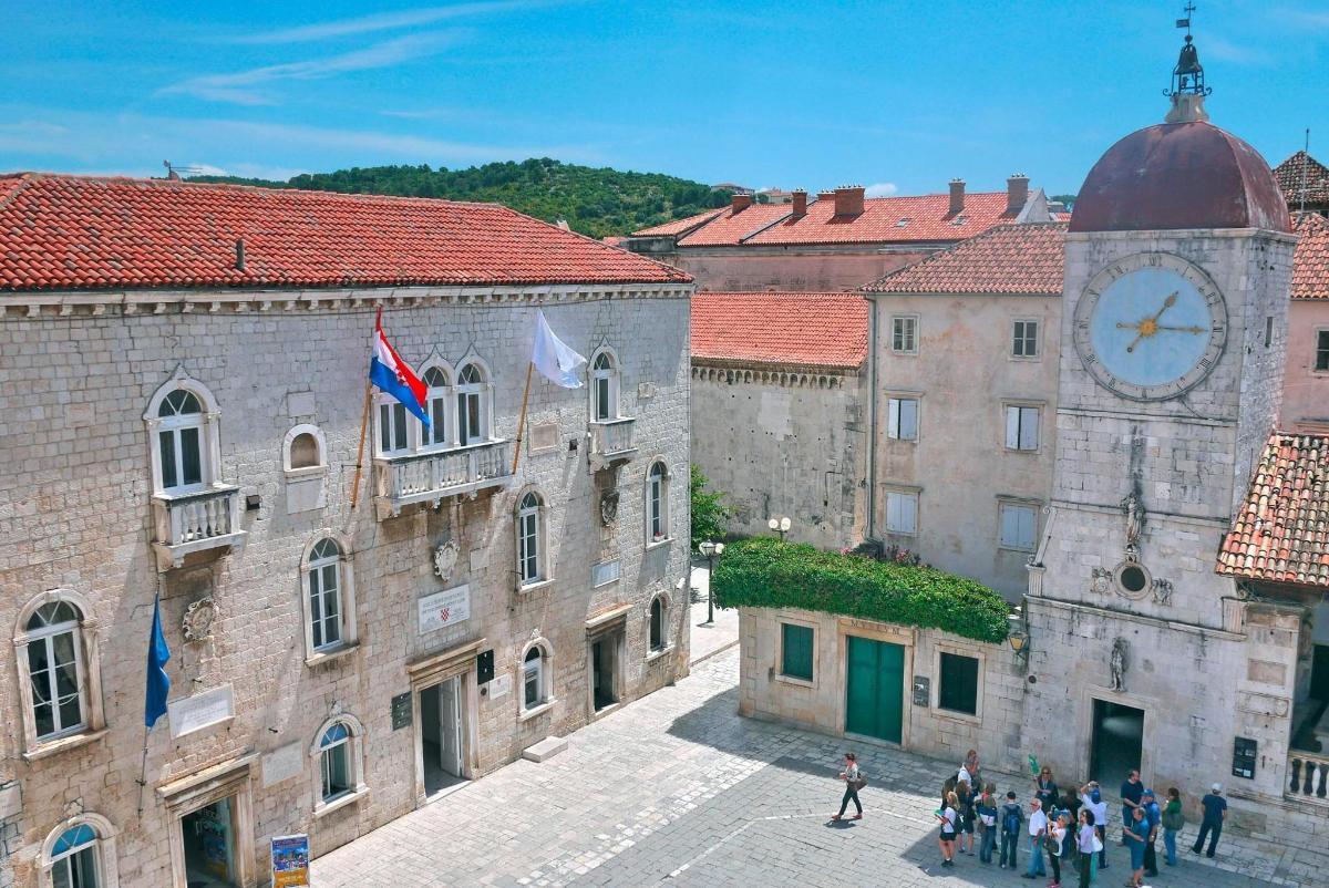 a group of people walking around a city with a clock tower