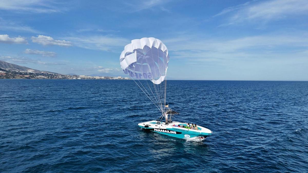 a blue and white boat in the water with a parachute