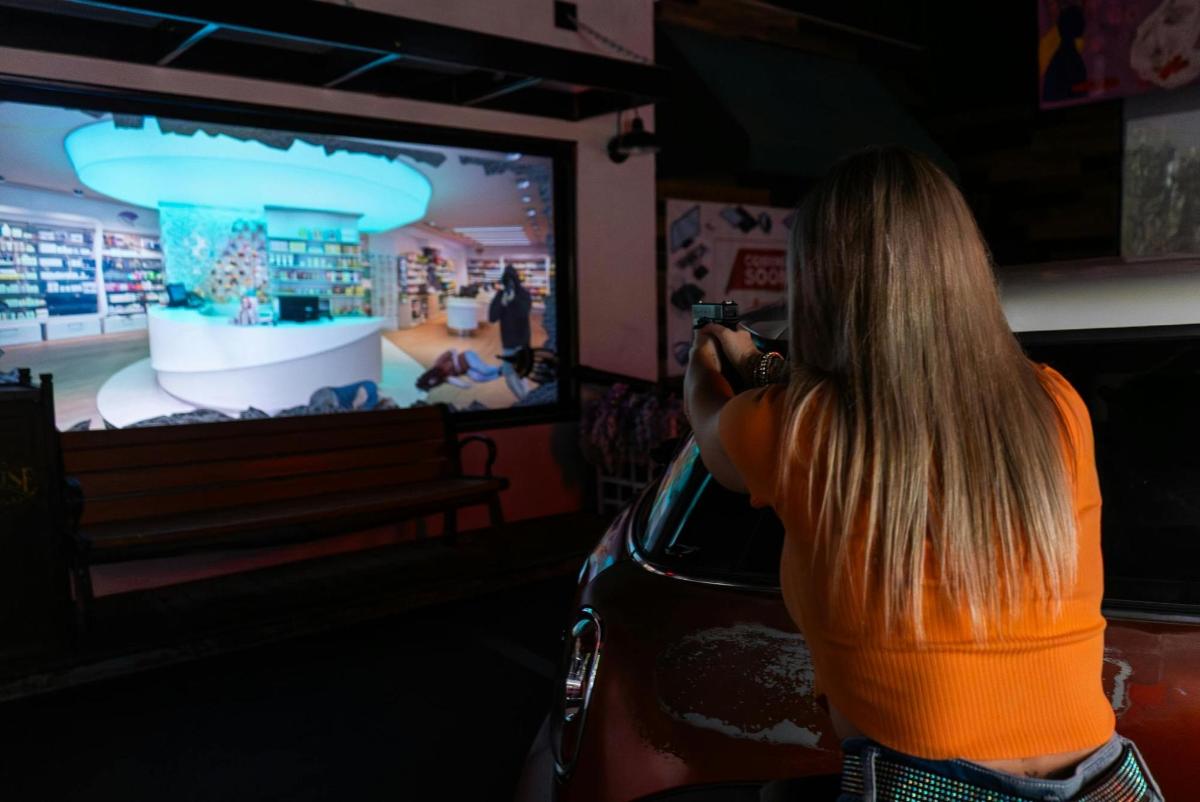 uma mulher tirando uma foto de um videogame na TV