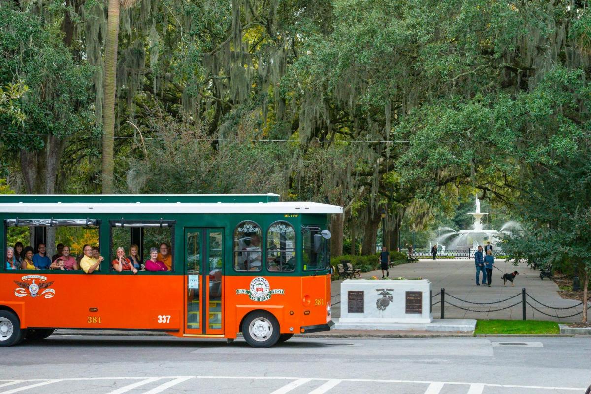 a trolley full of people riding in a park