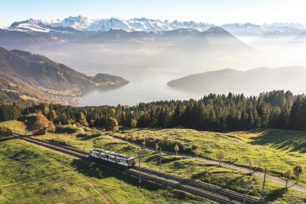 a train traveling through a valley with a lake and mountains