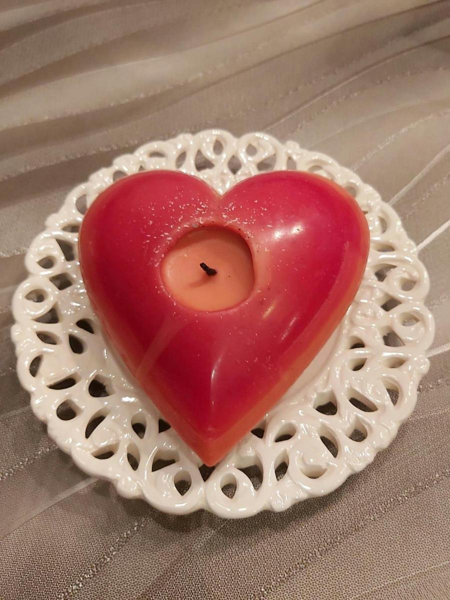 a red heart shaped candle sitting on a table