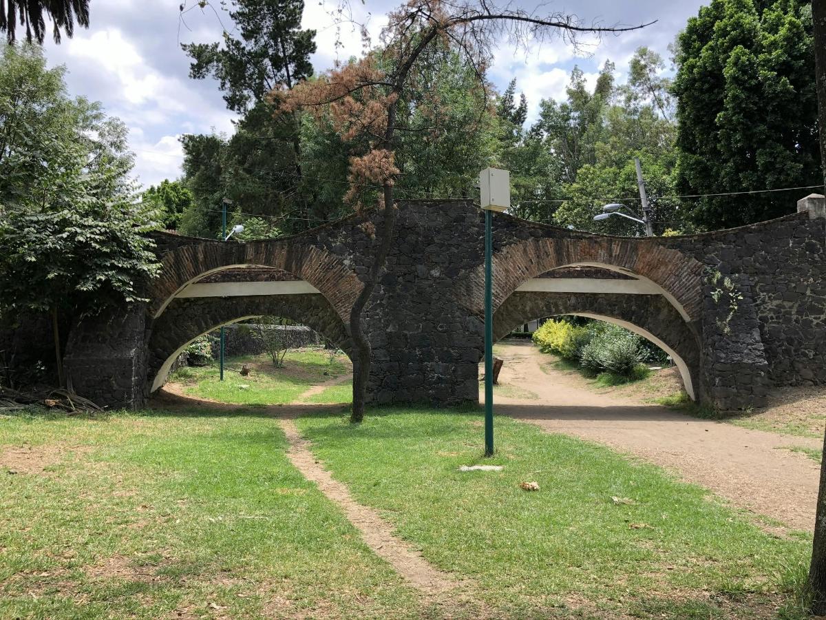 a stone bridge with two arches in a park