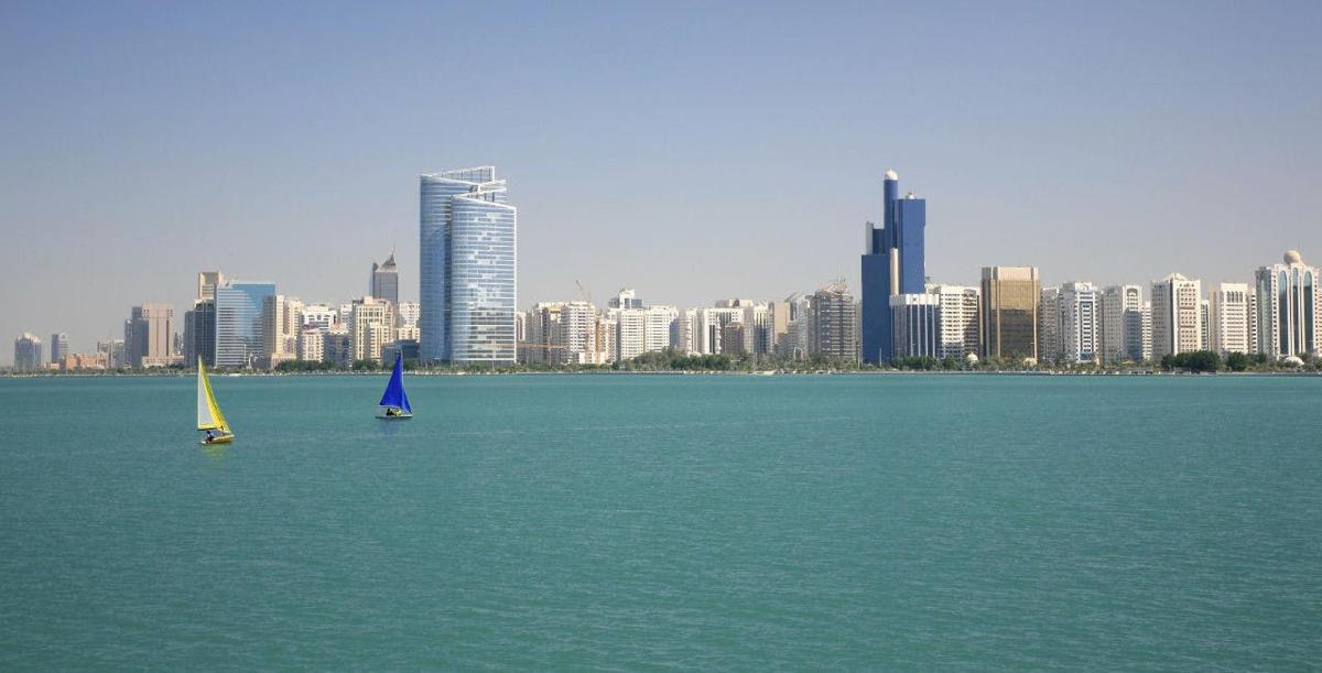 two sailboats in the water in front of a city