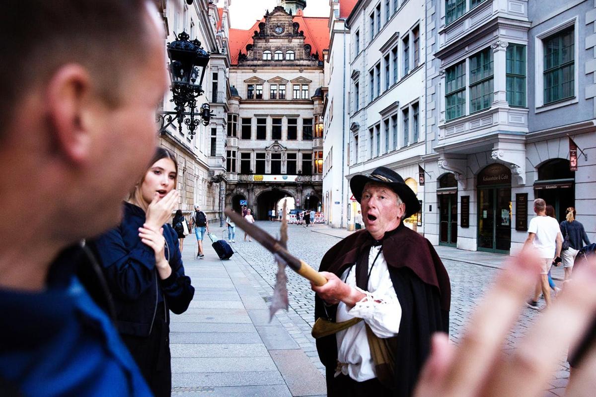 a man standing on a city street holding a wand