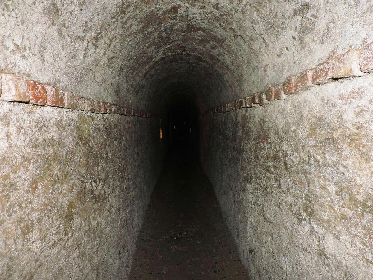 a tunnel in a stone wall with a light at the end