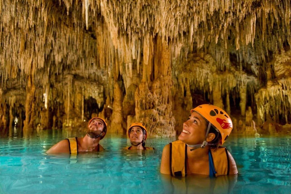 three people in a swimming pool in a cave