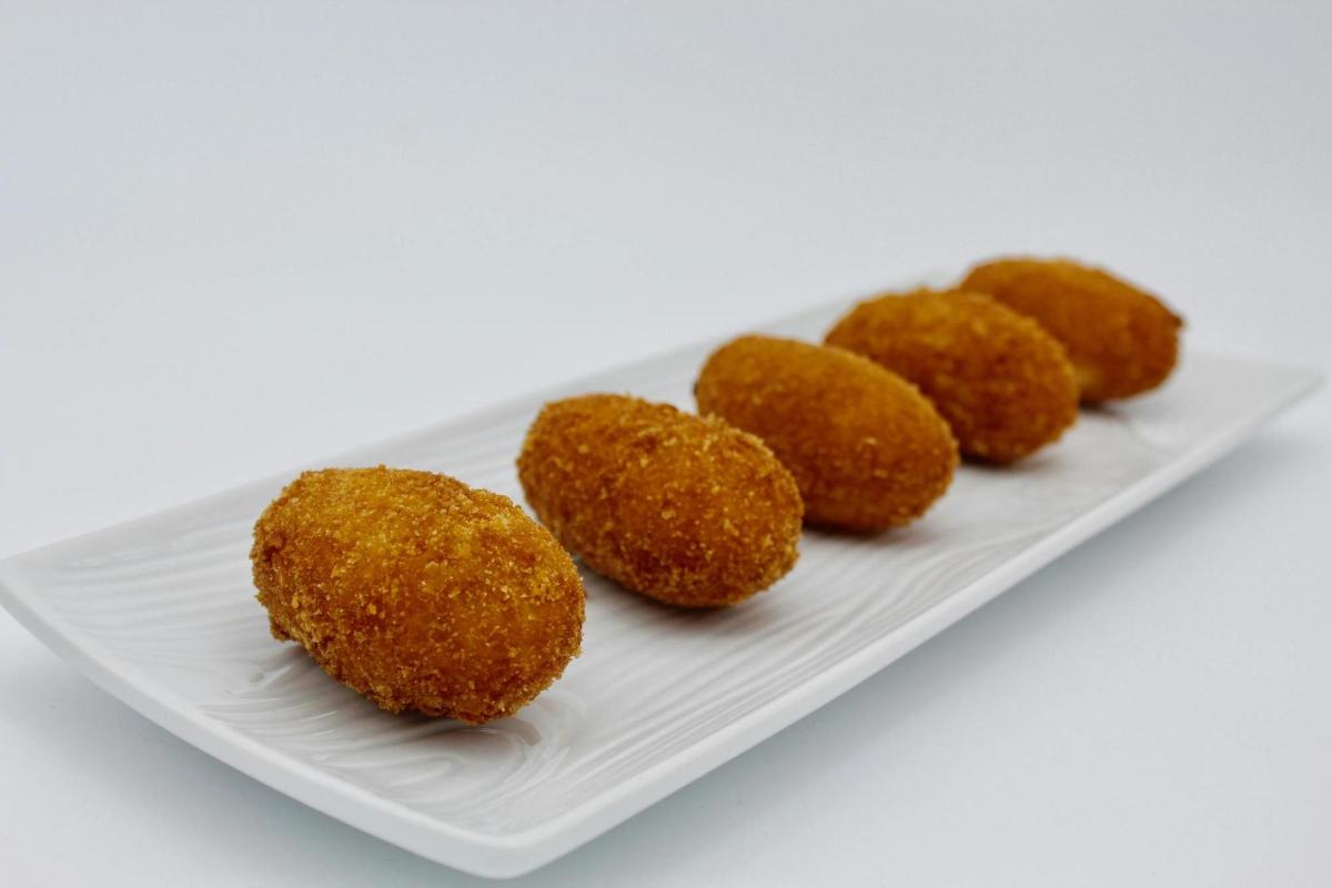 a white plate with four fried food on it