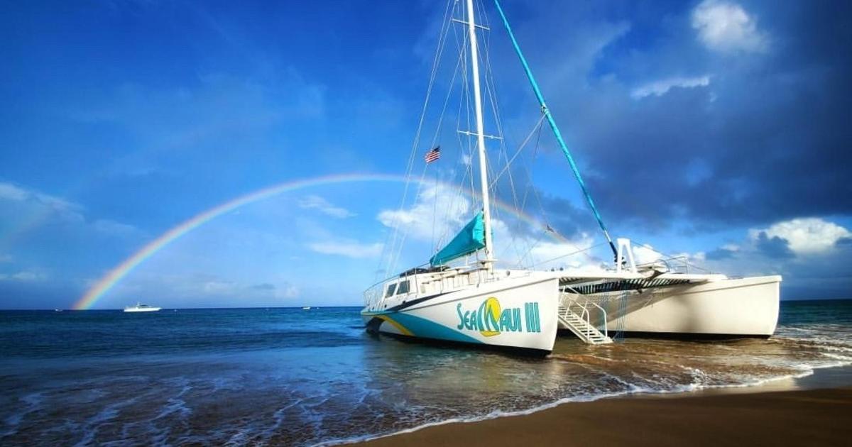 a boat sitting on the beach with a rainbow in the background