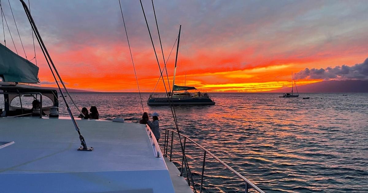 a group of people on a boat in the water at sunset