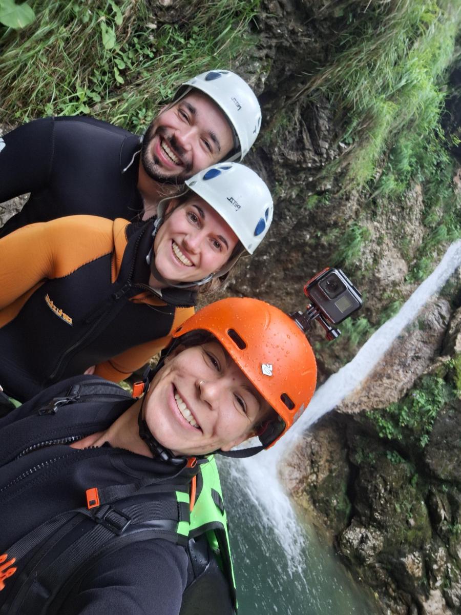 a group of three people wearing helmets on a waterfall