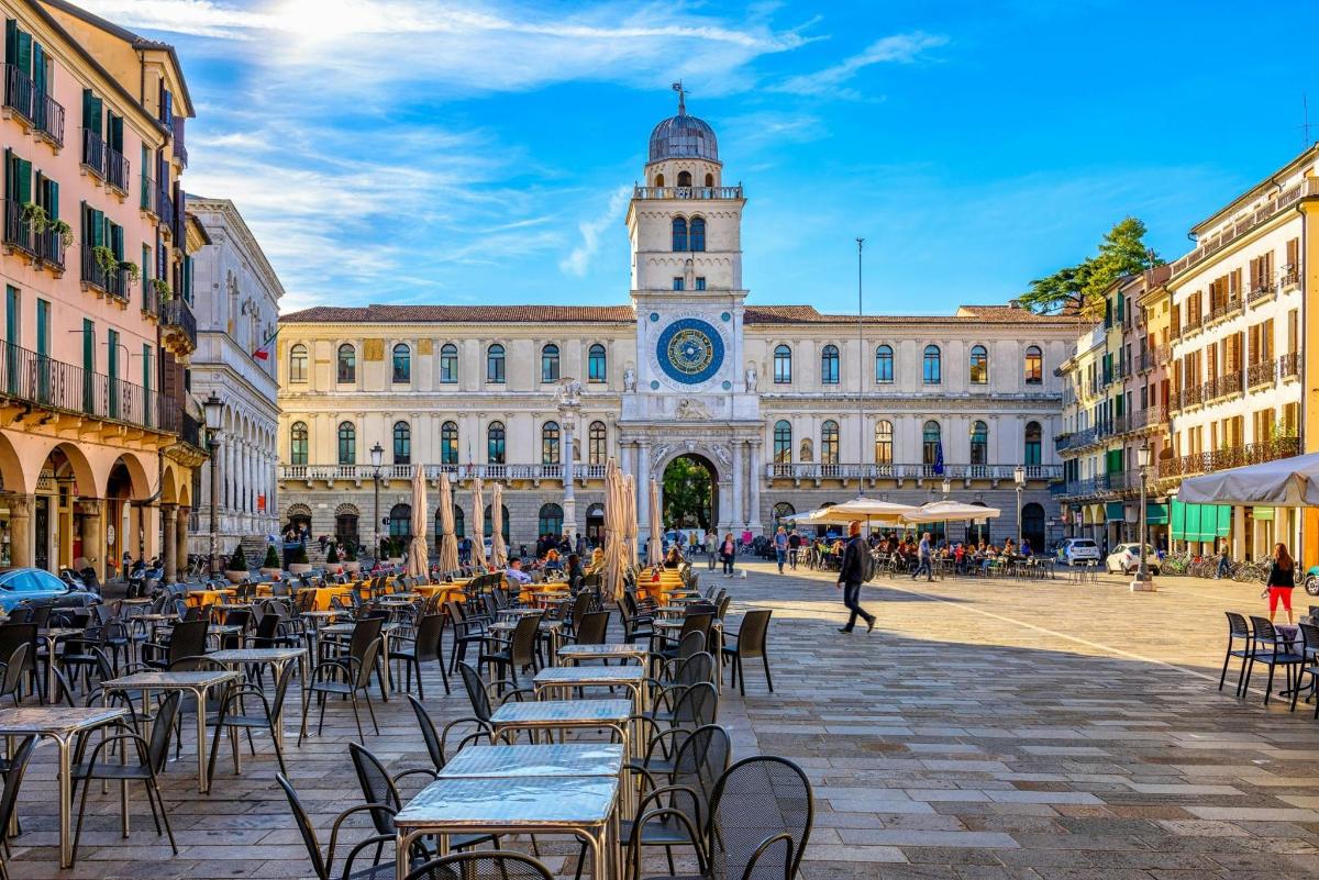a city square with tables and chairs in front of a building