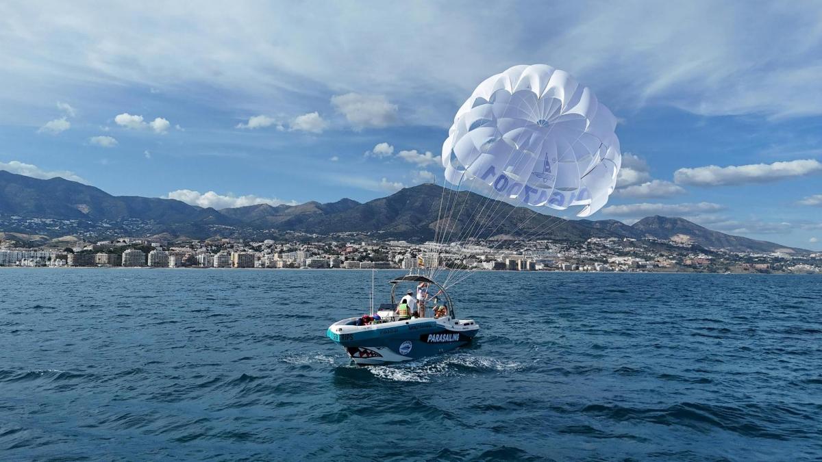 a small boat in the water with a parachute