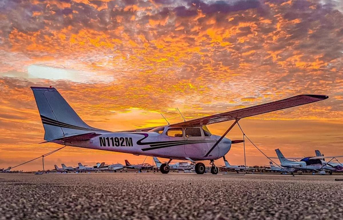 a small plane parked on a runway with a sunset