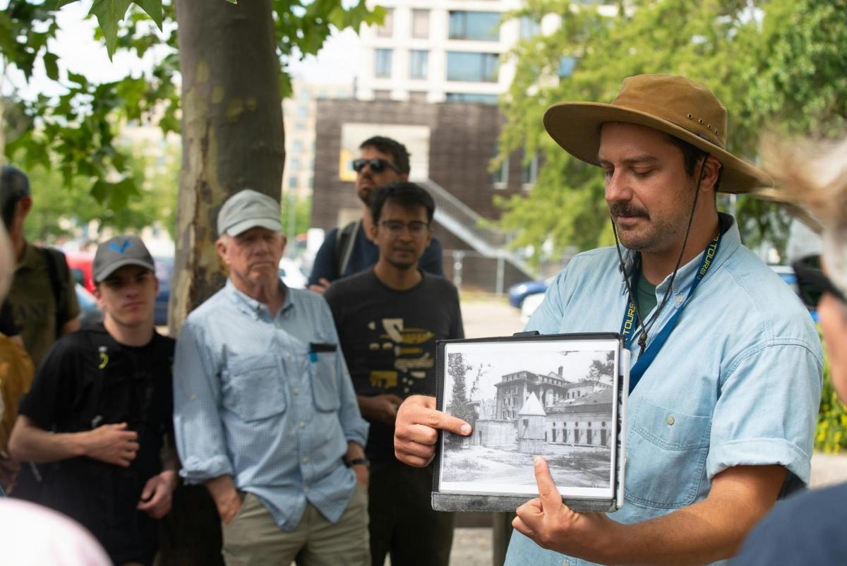 a man in a hat holding a picture of a building
