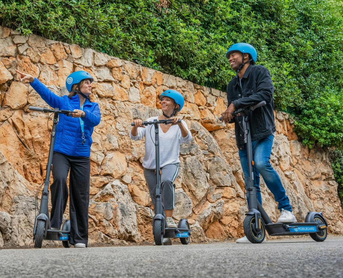 a group of three people riding on scooters