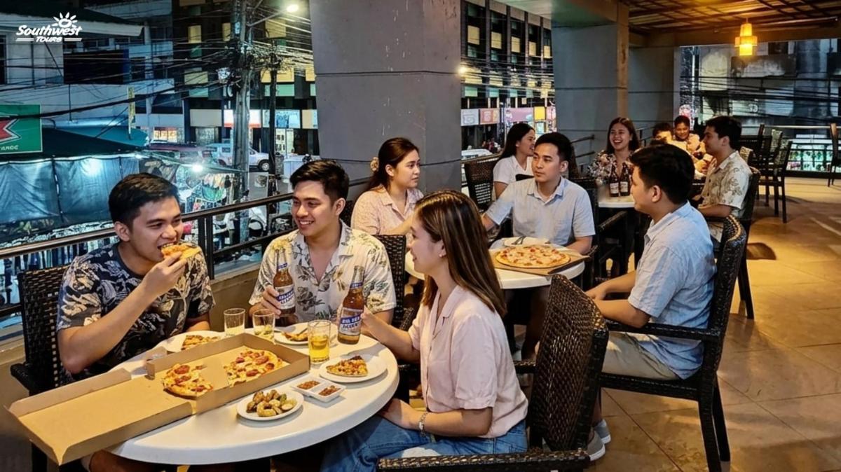 a group of people sitting at tables eating pizza