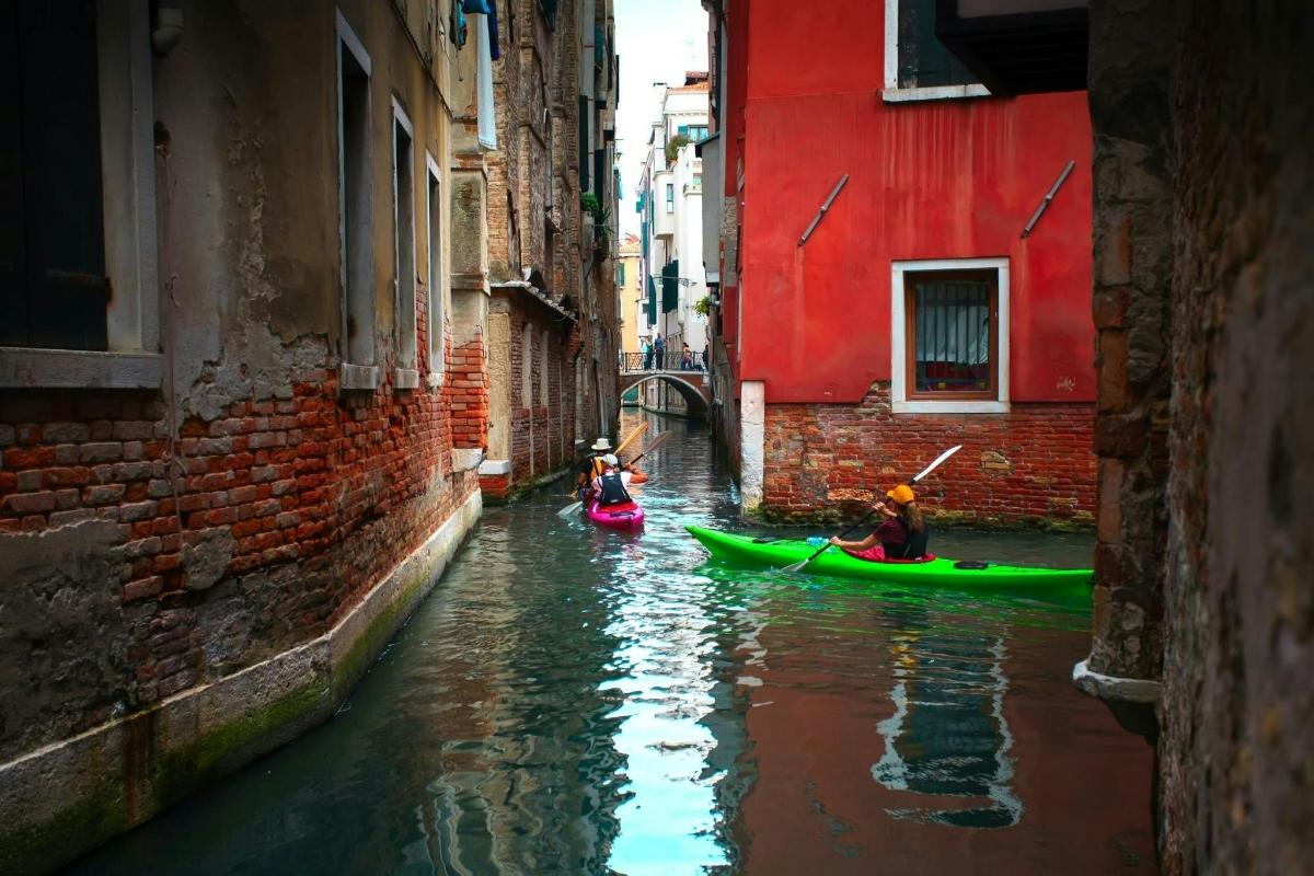 two people in kayaks on a canal in an alley
