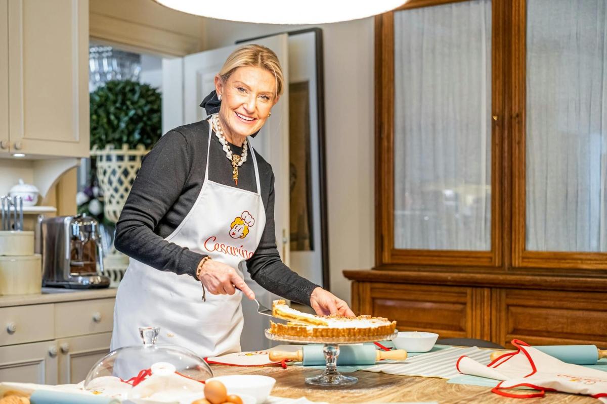 a woman in a kitchen cutting a cake