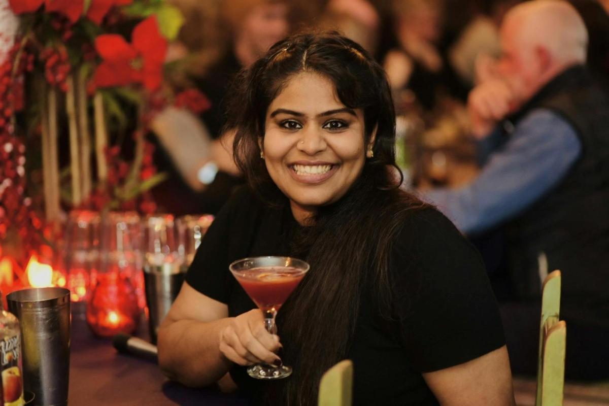 a woman sitting at a table holding a drink
