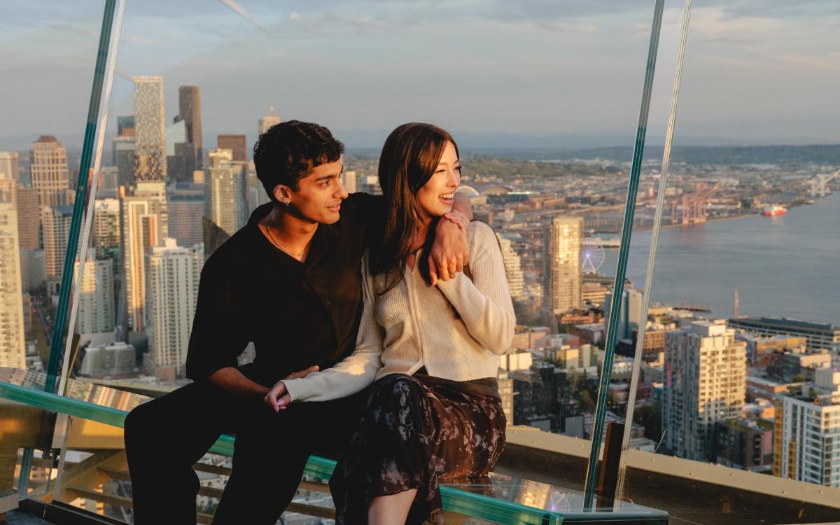 a man and a woman sitting on top of a skyscraper