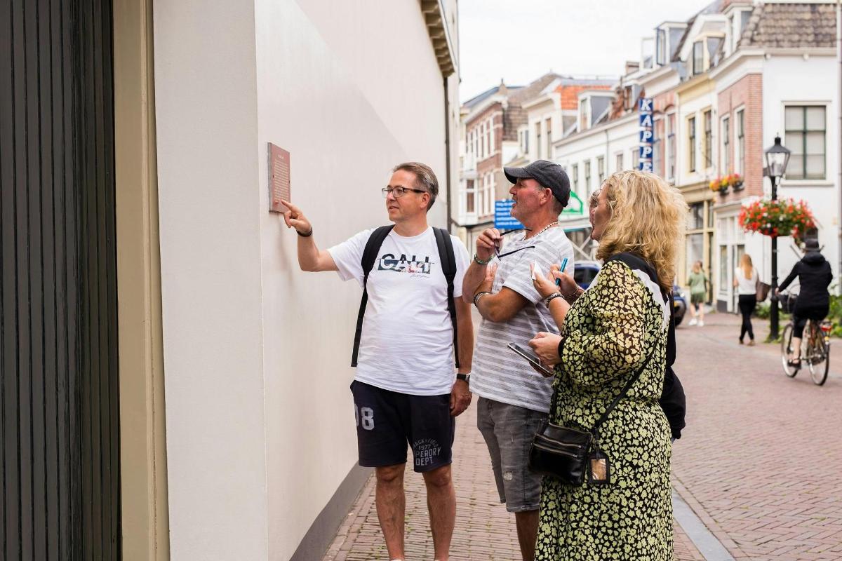 two men and a woman standing next to a wall