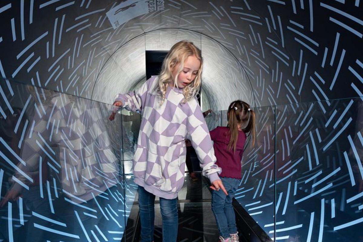 two girls are standing in a tunnel with a wall