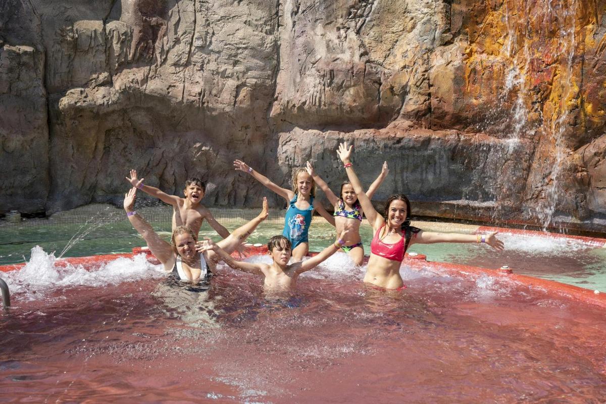 a group of people in the water at a waterfall