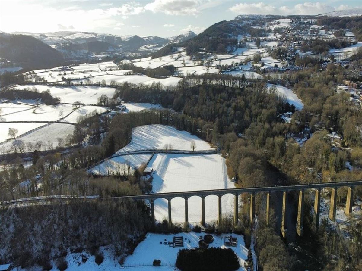 an aerial view of a snow covered valley with a bridge